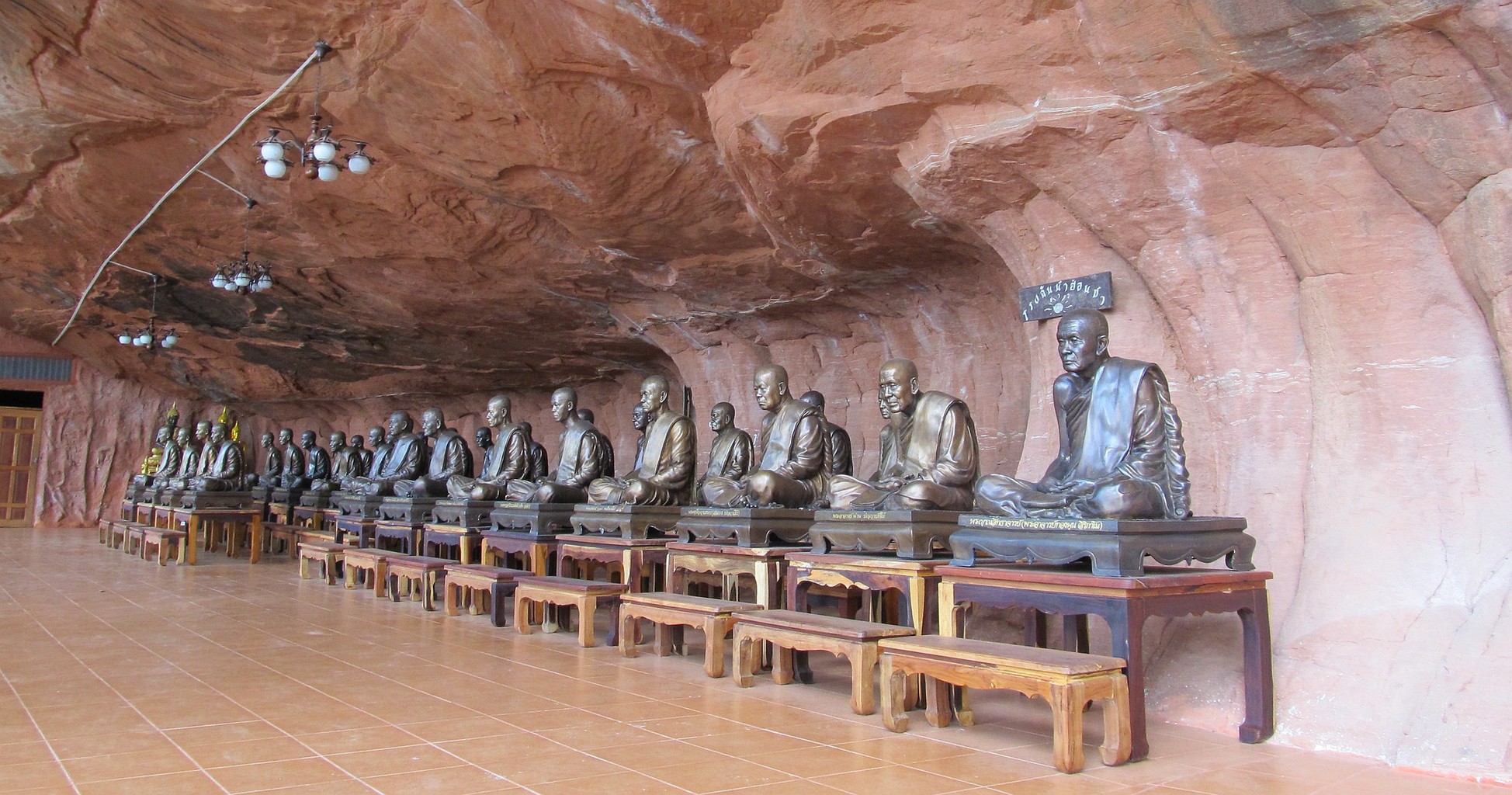 Bronzové sochy arahatů pod skalním převisem Wat Phu Thok - Bueng Kan