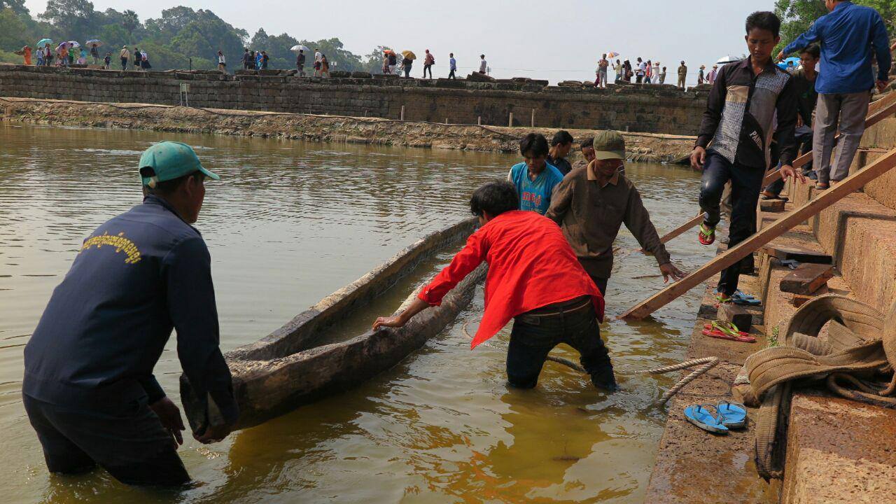 Dělníci přemisťují osm set let starý člun do vodní nádrže obklopující Angkor Wat